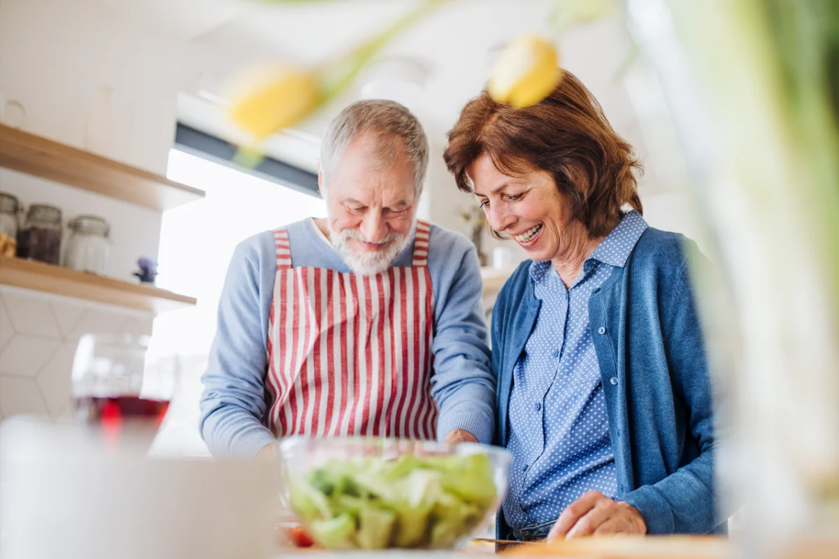 Mann und Frau bereiten einen Salat in einer modern eingerichteten Küche